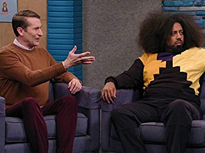 Reggie Watts Wears a Purple and Yellow Quilted Sweatshirt